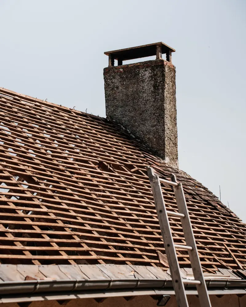 Toiture en tuiles en cours de rénovation avec cheminée